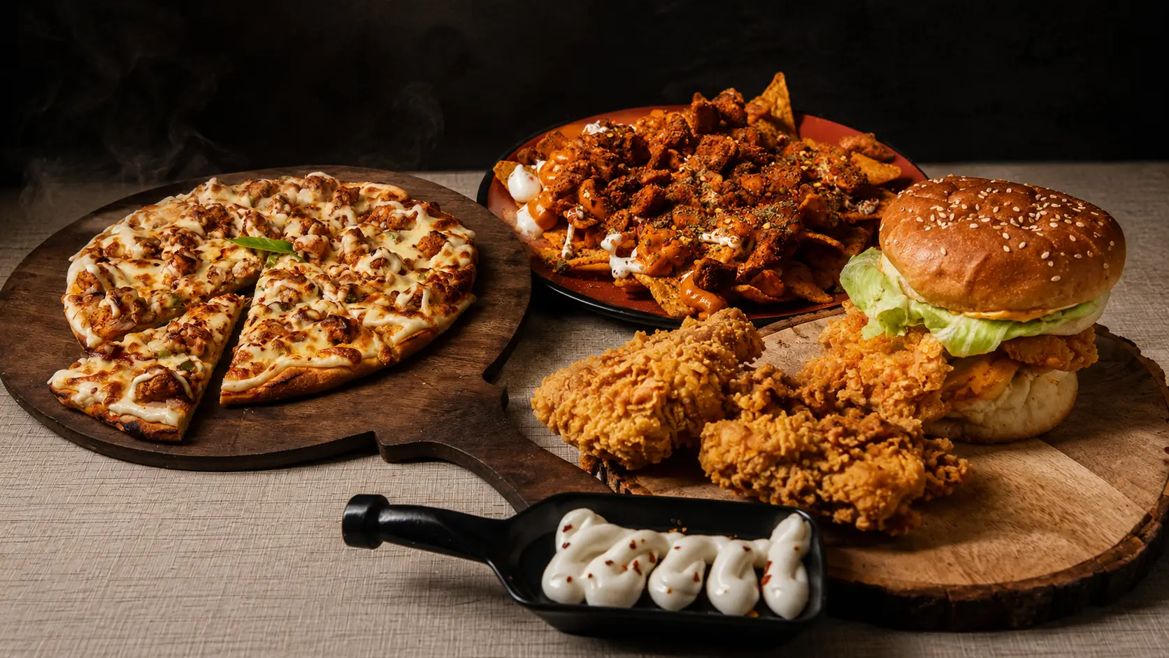 A chicken pizza, loaded nachos, fried chicken strips and a crispy chicken burger on wooden boards at Black Bird Cafe & Restaurant, Vellore